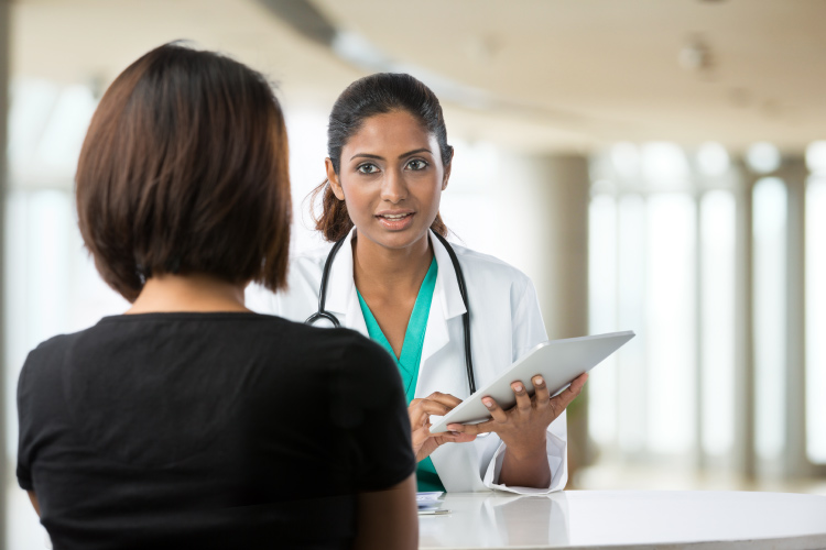 A nurse with a tablet talking to a patient.