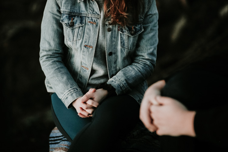 Two people sitting with folded hands.