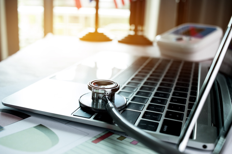  Close-up of a stethoscope on a desk with a laptop.