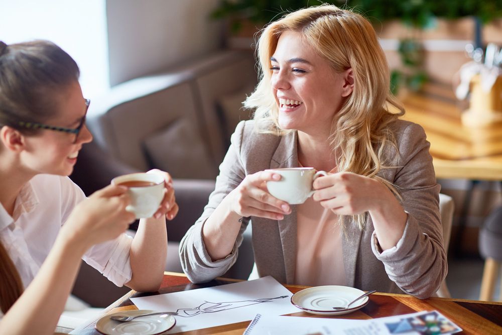 Two friends laughing over cups of tea.