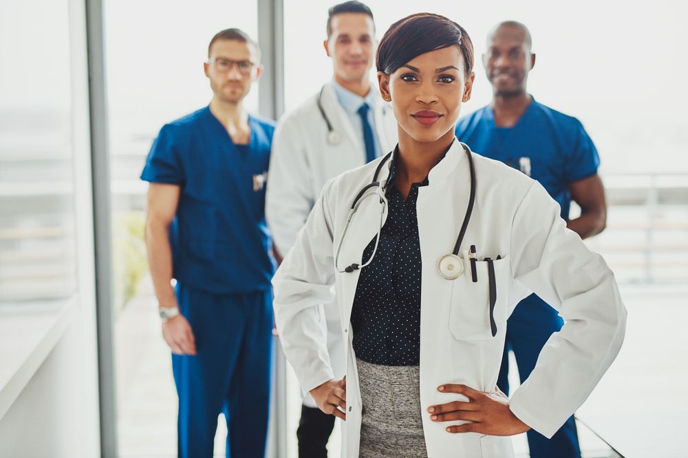 Female nurse leader looking confident with male nurses standing behind her