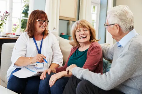 Social worker sitting on a sofa with elderly couple